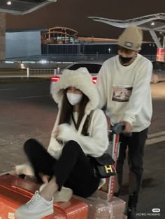 two people wearing masks and sitting on luggage