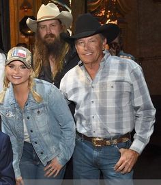 two men and a woman posing for a photo in front of a building with cowboy hats on