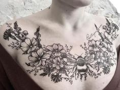 a woman wearing a black and white tattoo on her chest with flowers in the middle