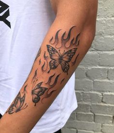 a man's arm with butterflies on it and flames coming out of the back