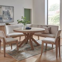 a round table with four chairs around it in a living room next to a couch