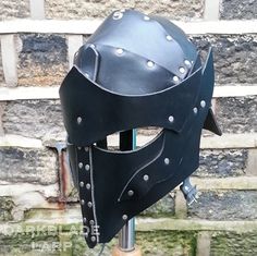 a black helmet with spikes on it sitting next to a brick wall