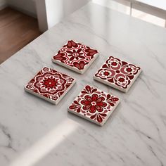 four red and white coasters sitting on top of a marble table