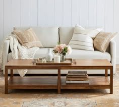 a living room with a couch, coffee table and books on the floor in front of it