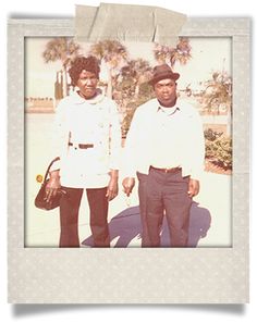 two men are standing next to each other in front of palm trees and the man is wearing a hat