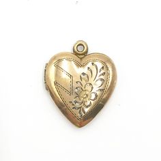 "Vintage Gold Heart Shaped Engraved Photo Locket. The locket is a lovely vintage 12K gold filled over sterling silver heart shaped locket. It has an engraved design on the front of a heart and flower. It snaps shut and contains two frames inside for your photos. The locket is marked 12K on STERLING. This piece is on good vintage condition with slight darkening on the bail where it meets the heart.   15/16\" l x 3/4\" w 3/8\" projection 3 grams Good vintage condition" Vintage Personalized Locket Necklace For Valentine's Day, Vintage Personalized Open Heart Jewelry, Gold Etched Locket Necklace, Heirloom Engraved Locket Necklace For Valentine's Day, Vintage Etched Locket Necklace For Anniversary, Vintage Open Heart Engraved Locket Necklace, Vintage Gold Etched Locket Necklace, Vintage Etched Locket Necklace For Keepsake, Vintage Engraved Open Heart Locket Necklace