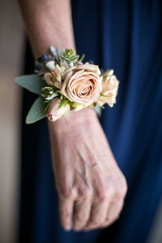 an older woman's hand holding a bouquet of roses and succulents