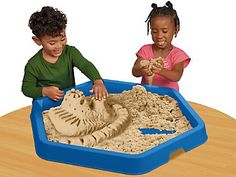 two children playing with sand in a blue tray