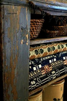 an old wooden shelf with baskets and rugs on the bottom, in front of it