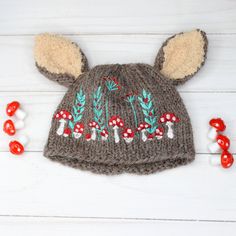 a knitted hat with ears and mushrooms on it, next to candy candies