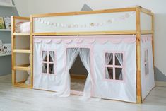 a pink and white tent bed in a child's room