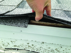 a hand is pointing at the gutter on top of a roof