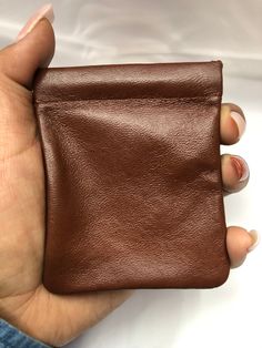 a woman's hand holding a brown leather wallet