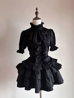 Step into the world of gothic elegance with our Black Jabot Collar Gothic Prince Style Ouji Short Sleeves Shirt. This exquisite piece features a refined jabot collar, exuding an air of aristocratic charm. The lace-up detail at the back not only adds a touch of classic sophistication but also ensures a perfect fit, accentuating your slim waist. This shirt combines the timeless allure of gothic fashion with the regal essence of prince-style attire.   	 		 			Size 			S 			M 			L 			XL 		 		 			Full Fitted Black Blouse With Doll Collar, Black Doll Collar Blouse For Party, Black Fitted Top With Doll Collar, Black Gothic Short Sleeve Blouse, Fitted Short Sleeve Gothic Blouse, Elegant Tops For Halloween Costume Party, Elegant Halloween Costume Party Tops, Elegant Victorian Dress With Ruffles For Cosplay, Black Fitted Top With Stand Collar