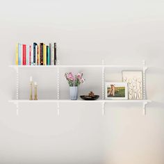 three white shelves with books and vases on them