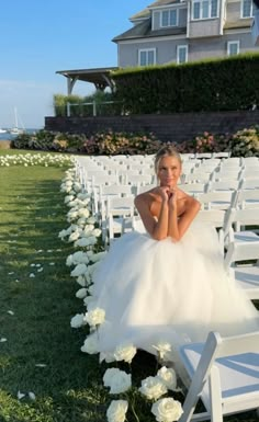 a woman in a wedding dress sitting on a chair with white flowers around her legs