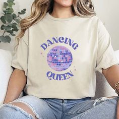 Step onto the dance floor with confidence and flair in our Dancing Queen graphic tee! Crafted with passion and designed for the free-spirited diva in you, this tee is a must-have addition to your wardrobe. Made from high-quality cotton blend fabric, our Dancing Queen tee offers both comfort and style in equal measure. The bold "Dancing Queen" graphic emblazoned on the front celebrates your love for dance and your undeniable queen status. 💃👑 Whether you're hitting the club, grooving at a concer Queen Status, Queen Tee, Statement Tees, Graphic Tops, Dancing Queen, Free Spirited, Tees For Women, The Dance, The Club