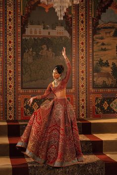 a woman in a red and gold dress is standing on steps with her arms up