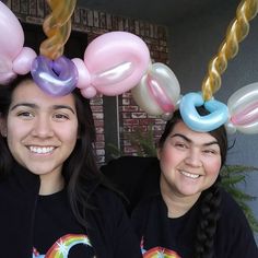 two girls with balloons on their heads smiling