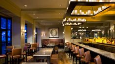 an empty bar with lots of chairs and lights hanging from the ceiling, along with marble counter tops