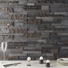 a white table topped with plates and glasses next to a wall covered in grey bricks