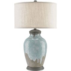 a table lamp with a blue and white vase on it's base, next to a beige linen shade