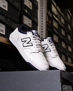 a pair of new balance shoes sitting on top of a shelf in a shoe store