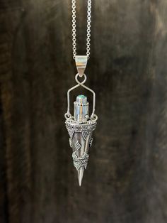 a silver necklace with a crystal pendant hanging from it's side