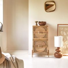 a living room with a lamp, dresser and pictures hanging on the wall above it