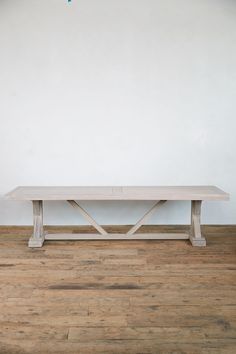 a wooden bench sitting on top of a hard wood floor next to a white wall