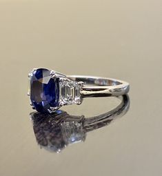 "DeKara Designs Collection Beautiful Modern/Art Deco Ceylon Blue Sapphire and Diamond Ring Metal- 90% Platinum, 10% Iridium Stones- Genuine Oval Ceylon/Sri Lanka Royal Blue Sapphire 3.75 Carats. Two Trapezoid Cut Diamonds F Color VS1 Clarity 1.09 Carats. Size-6 3/4. FREE SIZING Entirely Handmade, Classic and Timeless Art Deco Inspired Ceylon Oval Royal Blue Sapphire Diamond Engagement Ring. This ring is out of this world with the center Ceylon Sapphire being exceptional in quality, clarity, colo Timeless Blue Cushion Cut Ring, Platinum Three Stone Oval Rings, Classic Three-stone Sapphire Ring With Baguette Cut, Blue Three Stone Platinum Jewelry, Timeless Three-stone Blue Jewelry, Timeless Three Stone Blue Jewelry, Oval Sapphire Ring With Diamond Cut In Platinum, Oval Sapphire Diamond Ring With Diamond Cut, Timeless Blue Three-stone Jewelry