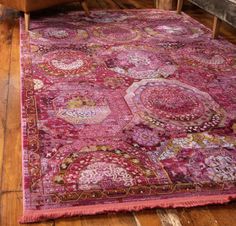 a large pink rug with medallions on it in the middle of a wooden floor