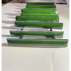 four green glass drawer pulls on a white table