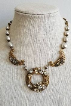 This is a vintage 1940s Original by Robert necklace. The necklace features a gold tone intricate metalwork with flowers and pearl tone details. The pearl tone beads are likely baroque style hand-painted glass given the era. The pearl tone beads range from brighter white to champagne to gray depending on the bead. The range of color could be intentional in design or from previous age and wear. The back of the center circle is signed on a palette shape. This necklace is in excellent condition.Cent Vintage Beaded Necklaces For Anniversary, Vintage Bridal Necklace With Intricate Design For Wedding, Antique Pearl Jewelry For Weddings, Vintage Gold Pearl Jewelry, Antique Gold Beaded Jewelry, Victorian Beaded Jewelry For Vintage Events, Vintage Beaded Jewelry For Events, Vintage Beaded Jewelry For Wedding, Antique Pearl Necklace For Wedding