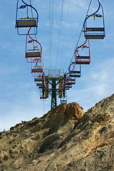 a ski lift going up the side of a mountain on a clear blue sky day