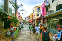 many people are walking down the street in front of shops