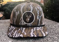 Deer patch bottomland trucker hat features a mesh back for breathability, front panel with a deer-themed design and an adjustable snapback closure for a customized fit. The hat combines a casual trucker style with outdoor elements, making it a popular choice for those who enjoy hunting or outdoor activities. Adjustable Camouflage Trucker Hat With Flat Brim, Adjustable Camouflage Trucker Hat With Curved Bill, Camouflage Trucker Hat For Outdoor Activities, Trucker Hat With Curved Brim For Hunting, Adjustable Camouflage Trucker Hat, Adjustable Trucker Hat For Hunting, Camouflage Baseball Cap Trucker Hat For Camping, Brown Snapback Trucker Hat For Hunting, Camouflage Trucker Hat For Outdoor