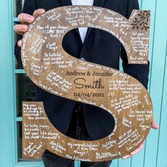 a man in a suit holding up a wooden letter