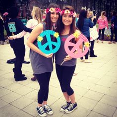 two women standing next to each other with peace signs on their heads and flowers in their hair