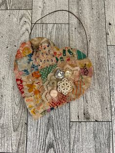 a heart shaped bag with buttons and other things on top of it, sitting on a wooden floor