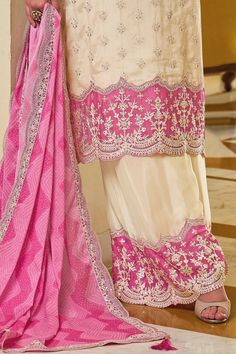 Experience elegance with the Ivory & Pink Chinon Silk Embroidered Palazzo Suit. Detailed thread work and sequins adorn this captivating design, making it the ideal choice for festivals and parties. Paired with a matching silk palazzo bottom and full size digital print dupatta, this suit exudes added elegance. Kameez chinon silk with embroidery work Palazzo chinon with embroidery work Dupatta chiffon silk with lace border, tassels Top Length: 46" Bottom Length: 40" Sleeves Length: 20" Santoon lining on top and bottom Work: Embroidered Side slit Neck Line: Round Occasion: party wear, festivals Dry clean Off White Traditional Wear With Dabka Work, Traditional Semi-stitched Cream Palazzo Set, Embroidered Dola Silk Fabric For Straight Kurta, Embroidered Beige Palazzo Set For Wedding, Beige Embroidered Palazzo Set For Wedding, Beige Embroidered Fabric For Reception, Silk White Salwar Kameez With Mirror Work, Off White Unstitched Traditional Wear With Mirror Work, Mirror Work Raw Silk Unstitched Suit