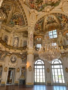 an ornate room with chandeliers and paintings on the walls, along with two large windows