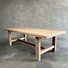 a large wooden table sitting on top of a cement floor next to a gray wall