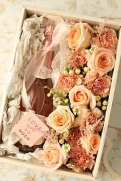 an open box with flowers and a bottle in it