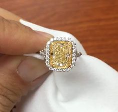 a woman's hand holding a fancy yellow diamond ring