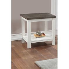 a white end table with a wooden top and shelf on the floor next to a rug