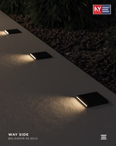 three square lights are lit up on the side of a white surface with black pebbles