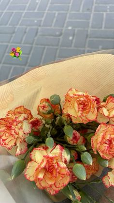 a bunch of red and yellow flowers sitting on top of a wooden table next to a brick wall