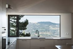 a kitchen with a large window overlooking the mountains and trees in front of it is shown