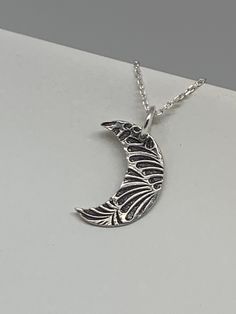 This unique silver moon necklace has been entirely handmade using .999 fine silver. It has been cut from fine silver precious metal clay, textured, fired and oxidized. The pendant hangs from a sterling silver diamond cut cable chain. This fine silver pendant features an embossed leaf print pattern and hangs 7/8 inches from top of ring to bottom of the moon shape. Pendant size: approximately 5/8 x 1/2 inches Chain length: adjustable at 16 and 18 inches can also be customized to whatever length ne Unique Silver Etched Necklaces, Sterling Silver Moon Engraved Necklace, Sterling Silver Moon Shaped Engraved Necklace, Unique Moon-shaped Engraved Necklace, Unique Moon Shaped Engraved Necklace, Unique Engraved Moon-shaped Necklace, Artistic Engraved Sterling Silver Necklaces, Artistic Engraved Sterling Silver Necklace, Artisan Moon Charm Necklaces